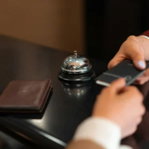 A close-up of a hotel check-in process with a smartphone and card transaction at the reception desk.