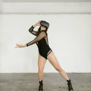 A woman in dance attire performs with a VR headset in an urban studio setting.