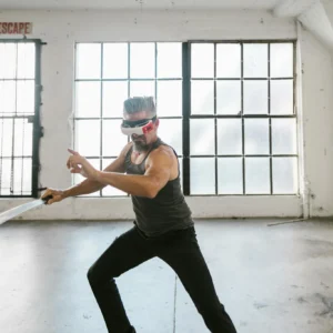 Man with VR headset practicing virtual sword fighting in an industrial-style loft studio. Futuristic workout concept.